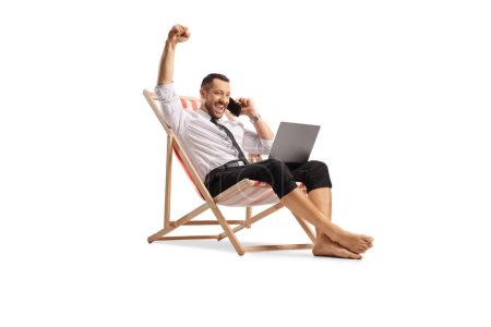 Téléchargez les photos : Bussinesman heureux sur une chaise de plage en utilisant un ordinateur portable et un smartphone isolé sur fond blanc - en image libre de droit