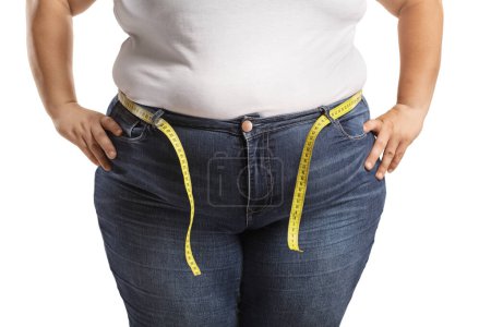 Foto de Cuerpo femenino con sobrepeso en jeans con cinta métrica alrededor de la cintura aislada sobre fondo blanco - Imagen libre de derechos