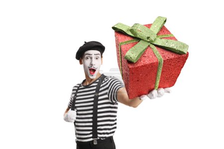 Téléchargez les photos : Mime tenant une boîte cadeau rouge isolée sur fond blanc - en image libre de droit
