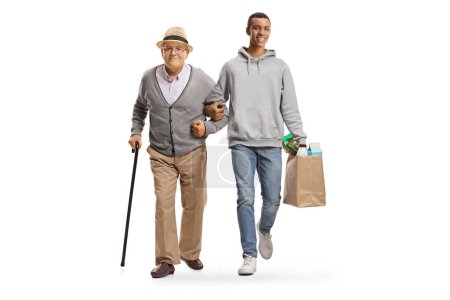 Téléchargez les photos : Jeune homme afro-américain avec des sacs d'épicerie marchant avec un homme âgé isolé sur fond blanc - en image libre de droit