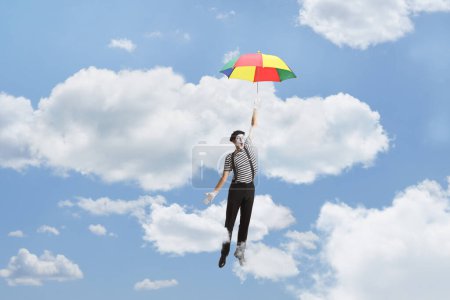 Téléchargez les photos : Mime avec un parapluie volant dans le ciel - en image libre de droit