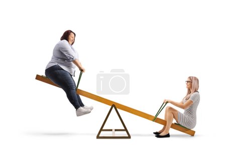 Photo for Slim and overweight woman playing on a seesaw isolated on white background - Royalty Free Image