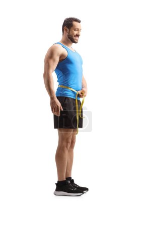 Photo for Full length shot of a man in sportswear measuring waist isolated on white background - Royalty Free Image