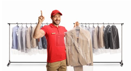 Photo for Worker at dry cleaners holding a suit on a hanger with a plastic cover and pointing up isolated on a white backgroun - Royalty Free Image