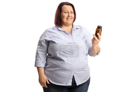 Foto de Mujer con sobrepeso sosteniendo una botella de pastillas y mirando a la cámara aislada sobre fondo blanco - Imagen libre de derechos