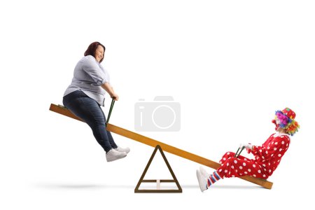 Photo for Corpulent woman playing on a seesaw with a clown isolated on white background - Royalty Free Image
