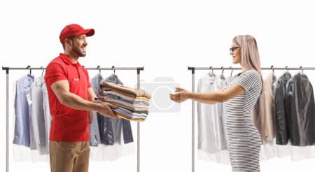 Foto de Man delivering a pile of folded clothes to a young woman at the dry cleaners isolated on a white background - Imagen libre de derechos