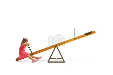 Photo for Sad little girl sitting on a seesaw alone isolated on white background - Royalty Free Image