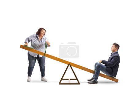 Photo for Overweight woman lifting a man on a seesaw isolated on white background - Royalty Free Image