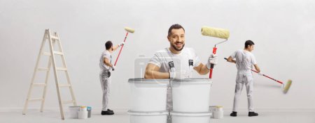 Téléchargez les photos : House painters with paint rollers and a ladder painting a wall - en image libre de droit