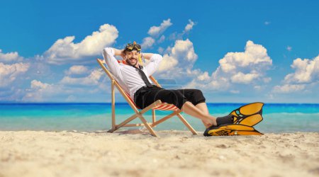 Téléchargez les photos : Homme d'affaires avec palmes de plongée et masque assis sur une chaise bech au bord de la mer - en image libre de droit