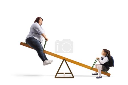 Téléchargez les photos : Corpulent woman playing on a seesaw with a schoogirl isolated on white background - en image libre de droit