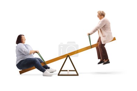 Téléchargez les photos : Young woman playing on a seesaw with an elderly woman isolated on white background - en image libre de droit