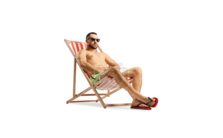 Photo for Fit man in swimwear sitting on a beach chair isolated on white background - Royalty Free Image