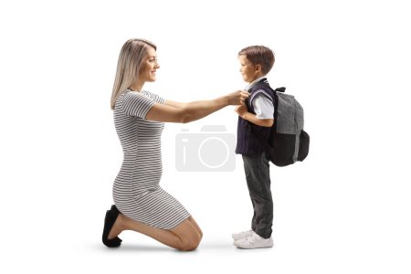 Foto de Full length profile shot of a mother helping son getting ready for school isolated on white background - Imagen libre de derechos