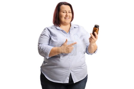 Foto de Overweight woman holding a bottle of pills and pointing isolated on white backgroun - Imagen libre de derechos