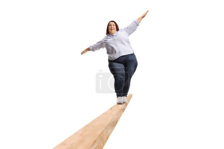 Téléchargez les photos : Full length portrait of an overweight woman walking on a wooden beam isolated on white background - en image libre de droit