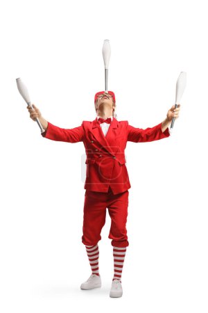 Téléchargez les photos : Interprète en costume rouge tenant des clubs de jonglerie avec la tête isolée sur fond blanc - en image libre de droit