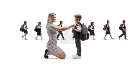 Foto de Madre ayudando a su hijo a prepararse para la escuela y otros niños caminando por la espalda aislados sobre fondo blanco - Imagen libre de derechos