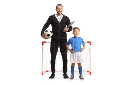 Foto de Niño y un entrenador de fútbol posando frente a un mini gol de fútbol aislado en el fondo blanco - Imagen libre de derechos