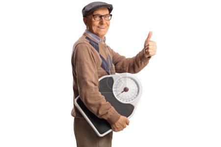 Photo for Elderly man holding a weight scale and gesturing thumbs up isolated on white background - Royalty Free Image