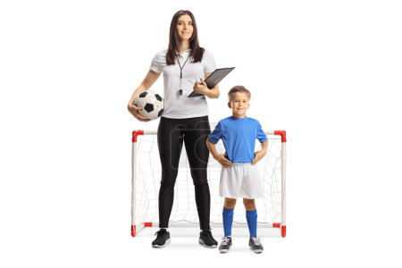 Photo for Female football coach with a whistle holding a clipboard and standing with a boy in front of mini goals isolated on white background - Royalty Free Image