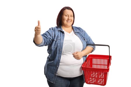 Photo for Corpulent woman with a shopping basket gesturing thumbs up isolated on white background - Royalty Free Image