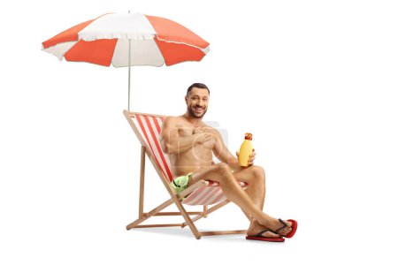 Téléchargez les photos : Jeune homme appliquant de la crème solaire sur la poitrine isolée sur fond blanc - en image libre de droit
