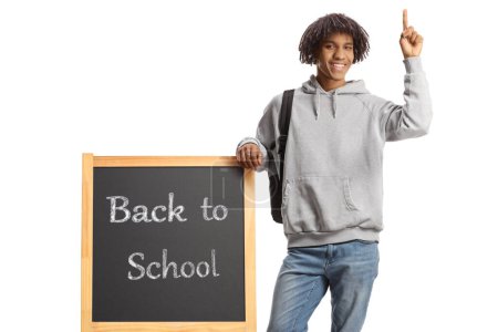 Photo for African american student leaning on a blackboard with text back to school and pointing up isolated on white background - Royalty Free Image