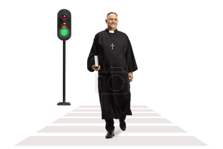 Photo for Priest walking at a pedestrian crossing and holding a bible isolated on white background - Royalty Free Image