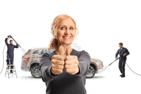 Foto de Mujer madura feliz con un SUV gesto pulgar hacia arriba signo en un lavado de coches aislado sobre fondo blanco - Imagen libre de derechos