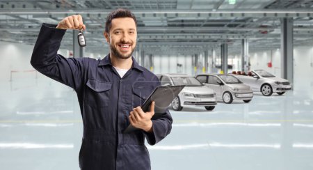 Photo for Auto mechanic holding key in a car garage - Royalty Free Image
