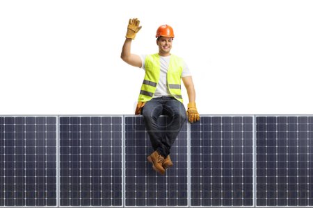 Photo for Full length portrait of a construction worker sitting on a solar panel isolated on white background - Royalty Free Image