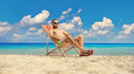 Photo for Man catching tan at the beach by the sea - Royalty Free Image
