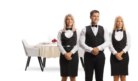 Foto de Servidores en uniformes posando frente a una mesa de restaurante aislados sobre fondo blanco - Imagen libre de derechos