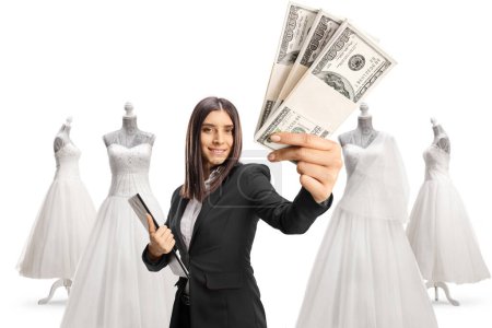 Photo for Businesswoman showing stacks of money in a bridal dress store isolated on white background - Royalty Free Image