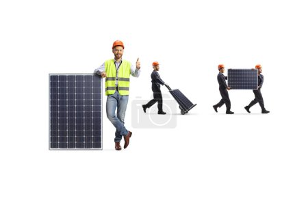 Foto de Ingeniero gestos pulgares hacia arriba y los trabajadores de la fábrica que llevan paneles fotovoltaicos aislados sobre fondo blanco - Imagen libre de derechos