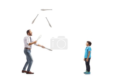 Photo for Full length profile shot of a boy watching a businessman juggling isolated on white background - Royalty Free Image