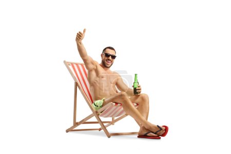 Photo for Man sitting at a beach chair holding a bottle of beer and gesturing thumbs up isolated on white background - Royalty Free Image