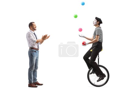 Téléchargez les photos : Plan de profil complet d'un homme applaudissant un mime sur un monocycle jonglant avec des balles isolées sur fond blanc - en image libre de droit