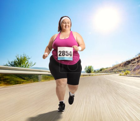 Foto de Mujer alegre con sobrepeso corriendo un maratón en un camino - Imagen libre de derechos