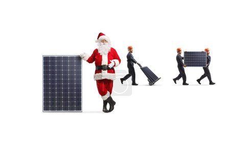 Foto de Santa Claus apoyada en un panel y trabajadores de la fábrica llevando fotovoltaica aislada sobre fondo blanco - Imagen libre de derechos