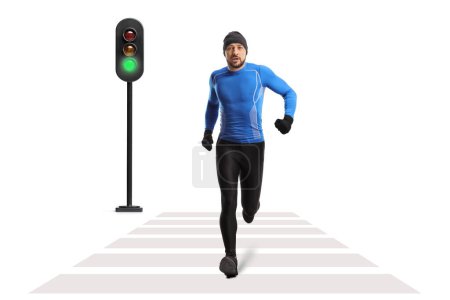 Foto de Retrato completo de un hombre en forma en invierno corriendo ropa trotando en un cruce peatonal - Imagen libre de derechos
