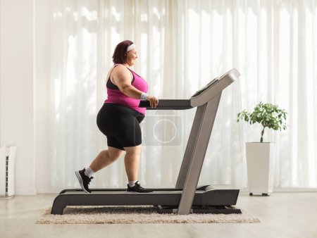 Photo for Overweight woman walking on a treadmill at home - Royalty Free Image