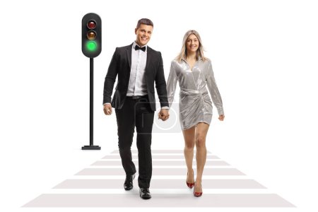 Photo for Full length portrait of a young couple in elegant clothes crossing a street and holding hands isolated on white background - Royalty Free Image