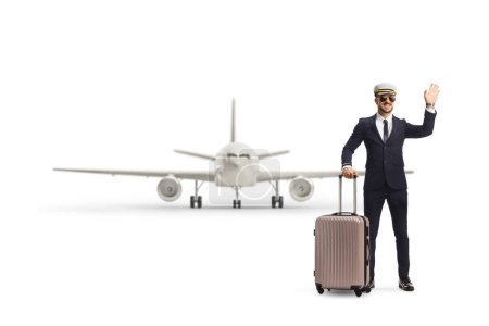 Téléchargez les photos : Pilote avec une valise devant un avion agitant à la caméra isolé sur fond blanc - en image libre de droit
