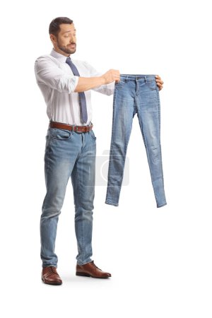 Photo for Pensive man looking at a small pair of jeans isolated on white back - Royalty Free Image