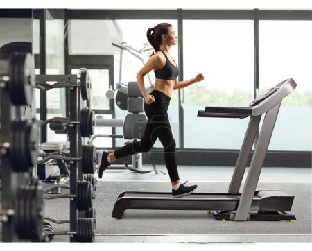 Photo for Full length profile shot of a young female in black leggings running on a treadmill at a gym - Royalty Free Image