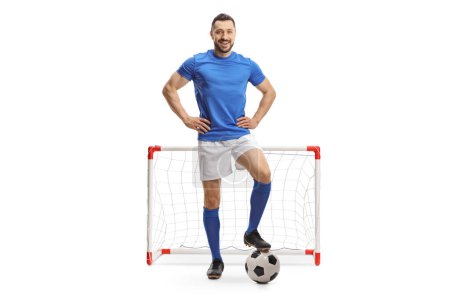 Foto de Retrato completo de un jugador de fútbol posando con una pelota frente a un mini gol aislado sobre fondo blanco - Imagen libre de derechos