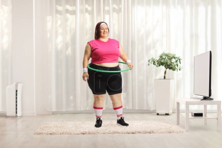Photo for Overweight woman with a hula hoop standing at home and smiling at camera - Royalty Free Image